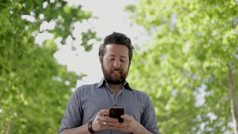 Happy-bearded-man-using-smartphone-outdoor